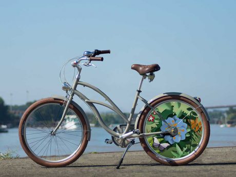 Vélo Beach Cruiser mixte pour homme ou femme au design fleuri. Collection Canopée avec une roue lenticulaire à l'arrière, pour vous démarquer lors de vos trajets
